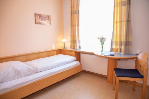 a bedroom with a bed and a desk and a window at Spectrum Kirche Exerzitien-und Bildungshaus auf Mariahilf in Passau