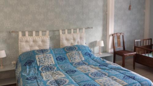 a bedroom with a bed with a blue comforter and a chair at LA VALLEE MARIAUX in Bossus-lès-Rumigny