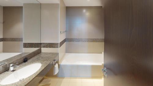 a bathroom with a sink and a tub at Hometown Apartments - Brand New 2BR Apartment in Dubai Wharf 2 in Dubai