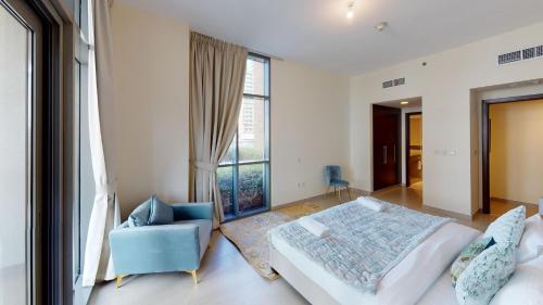a bedroom with a bed and a chair and a window at Hometown Apartments - Brand New 2BR Apartment in Dubai Wharf 2 in Dubai