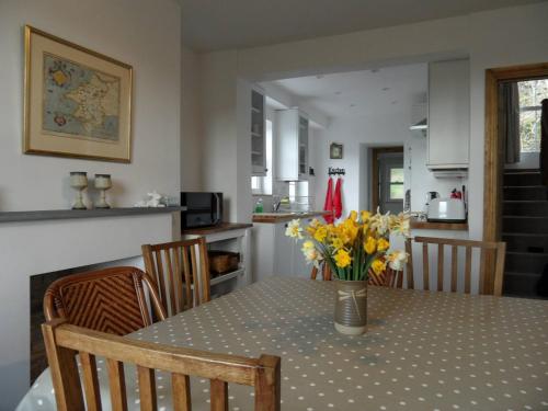 a dining room table with a vase of flowers on it at Farthings Hook Mill Holiday Cottage in Henrys Moat
