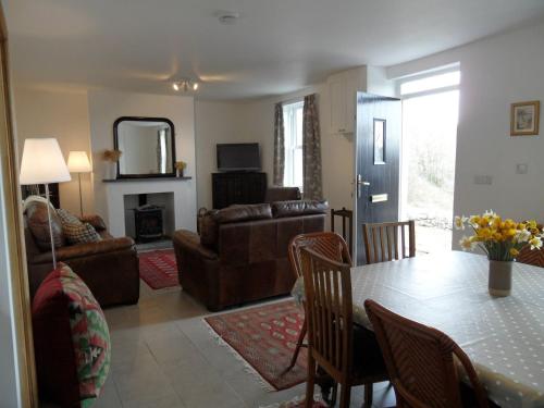 a living room with a table and a living room with a couch at Farthings Hook Mill Holiday Cottage in Henrys Moat