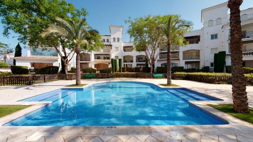 a swimming pool with palm trees in front of a building at Casa Pez Espada-A Murcia Holiday Rentals Property in Roldán