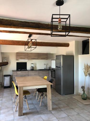 une cuisine avec une table en bois et un réfrigérateur dans l'établissement Logement au cœur du village de Rasteau, à Rasteau