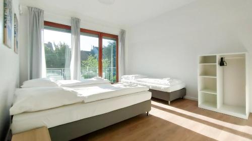 a white room with two beds and a window at RAJ Living - City Apartments with 2 , 3 and 6 Rooms - 15 Min to Messe DUS and Old Town DUS in Düsseldorf