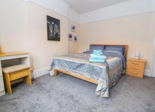 a bedroom with a bed with blue sheets and a desk at Seabreeze Apartment in Llandrillo-yn-Rhôs