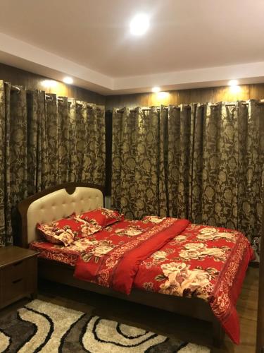 a bedroom with a bed with a red blanket at Kathmandu Sojourn-Your home away! (2BHK Apartelle) in Kathmandu