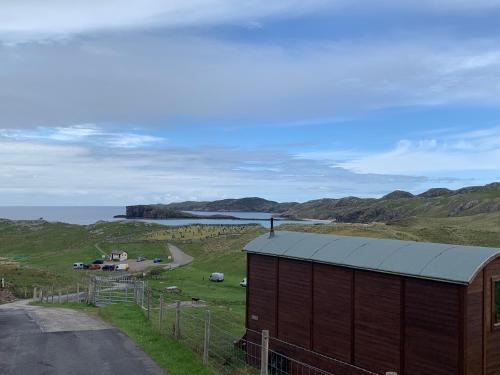 a building on the side of a road near the ocean at Eco Crofters Wagon by the Beach in Oldshoremore