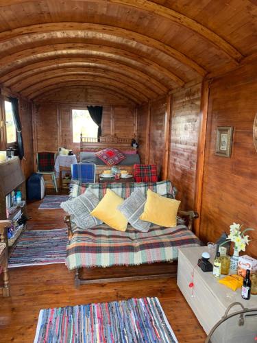 a bedroom with a bed and a couch in a room at Eco Crofters Wagon by the Beach in Oldshoremore