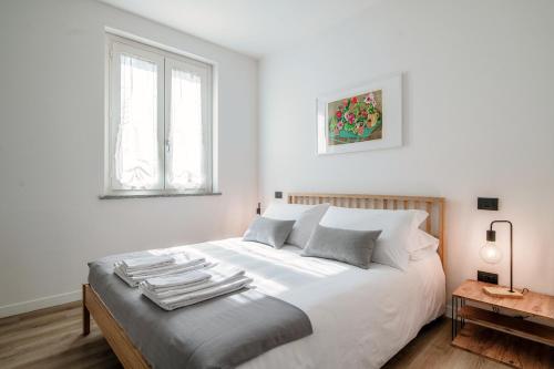 1 dormitorio blanco con 1 cama blanca grande y 2 ventanas en OLIVE TREE LAKE VIEW APARTMENT, en Bellagio