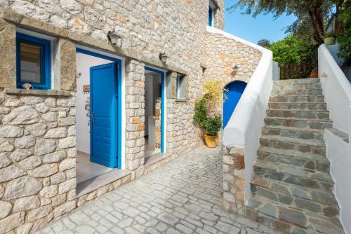 Casa de piedra con puertas y escaleras azules en Agnanti Beach Apartments, en Archangelos