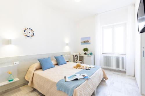 a white bedroom with a large bed with blue pillows at B&B La Rosa dei Venti, panoramico nel cuore di Vieste Vista mare Centro storico in Vieste