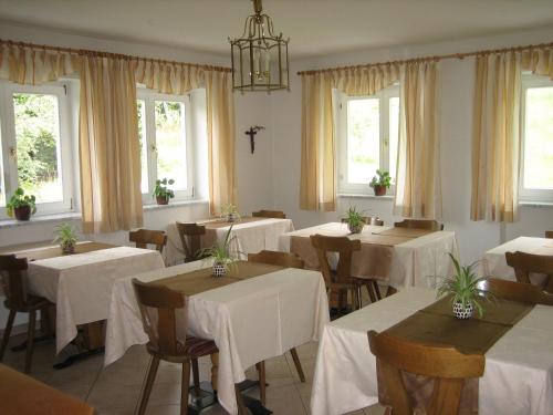 a restaurant with white tables and chairs and windows at Garni Sonnegg in Petersberg