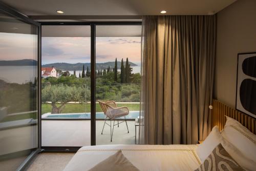 a bedroom with a bed and a view of a pool at Luxury Villa Ó - Dubrovnik in Orasac
