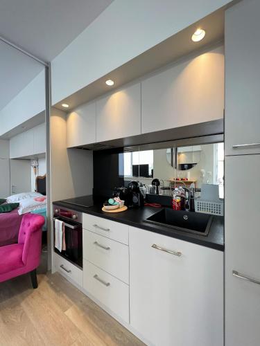 une cuisine avec des armoires blanches et un évier et un lit dans l'établissement Le Central Victoria IV - Central Point - 22m2, à Nancy