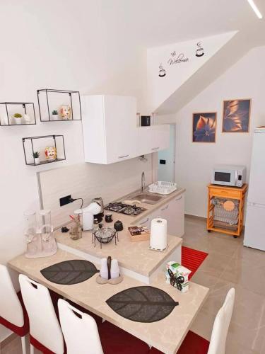 a kitchen with white cabinets and a table with chairs at Casa Ciuzza in Siracusa