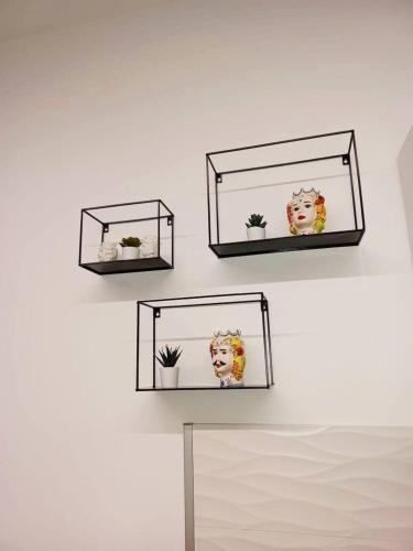 three shelves on a wall with plants in them at Casa Ciuzza in Siracusa
