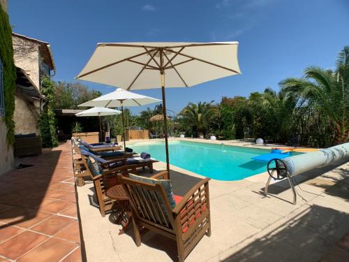 a pool with tables and chairs and an umbrella at Villa La Rose des Vents in Tourrettes