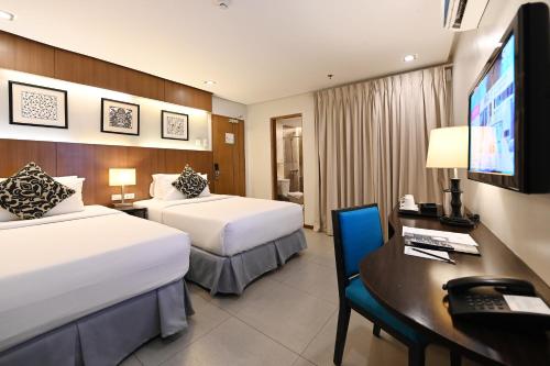 a hotel room with two beds and a desk and a television at St Mark Hotel in Cebu City