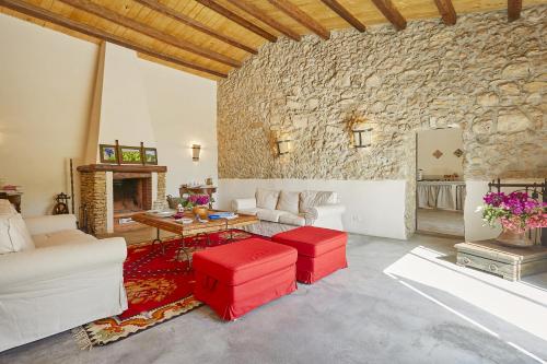 a living room with a stone wall and red stools at Casale Monte Kronio by Wonderful Italy in Sciacca