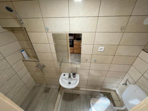 a bathroom with a sink and a toilet and a mirror at Perényi Pince és Vendégház Hajós in Hajós