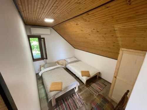 Cette chambre mansardée comprend 2 lits et un plafond en bois. dans l'établissement Perényi Pince és Vendégház Hajós, à Hajós