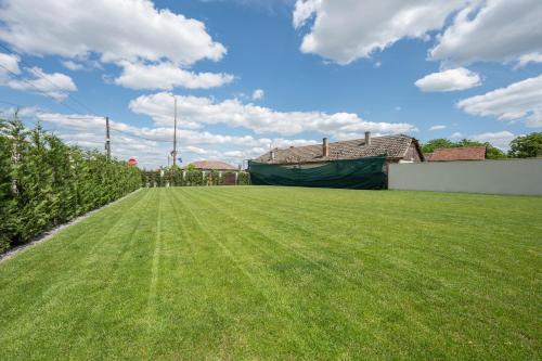 a large grassy yard with a building in the background at Klia in Sînmartin