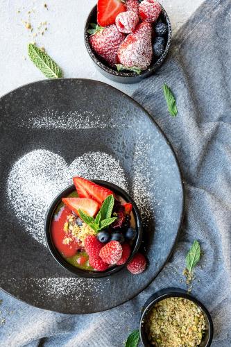 a plate with a bowl of fruit on a table at Radisson Blu Hotel Wroclaw in Wrocław