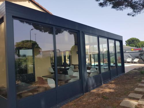 a building with glass doors and tables and chairs at Kyriad Carcassonne - Aéroport in Carcassonne