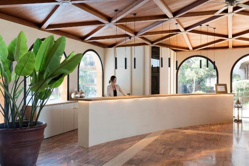 a woman standing behind a counter in a room with windows at Luna Park Hotel Yoga & Spa in Malgrat de Mar