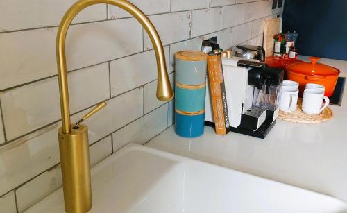 a kitchen sink with a gold faucet on a counter at The Farrier in Cheltenham