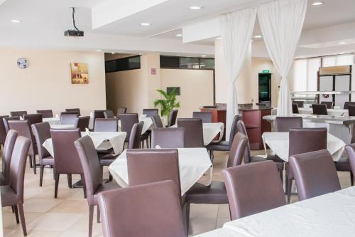 una sala da pranzo con tavoli e sedie bianchi di Resotel a Maputo