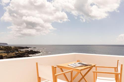 a table and two chairs on a balcony with the ocean at White Exclusive Suites & Villas in Lagoa
