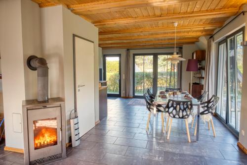 a dining room with a table and a fireplace at traumHaff - Strandhaus am Achterwasser. Design und Kunst auf Usedom, mit Kamin und Sauna in Quilitz