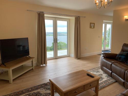 a living room with a couch and a flat screen tv at Highland Farm Cottages in Dingwall