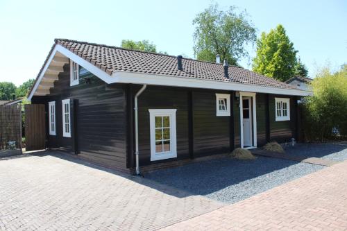 a small black house with white windows on a driveway at De Genten 1, vakantiewoning met jacuzzi in Ermelo