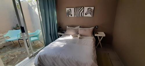 een slaapkamer met een wit bed en een raam bij Self-catering Studio, Unit 3 on Krupp in Windhoek