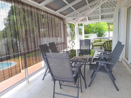 a screened in porch with chairs and a table at Charmante villa avec piscine proche plage in Flic-en-Flac