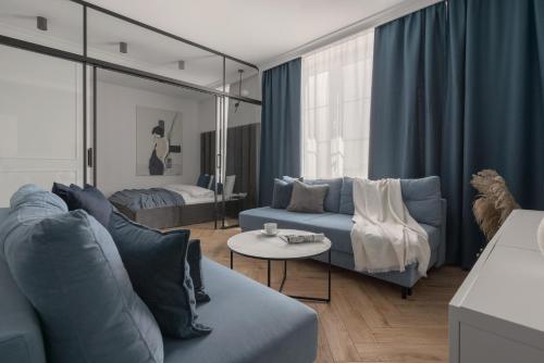 a living room with a blue couch and a bed at APARTIO ROOMS Katowice in Katowice