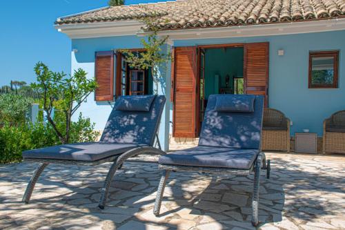 2 sedie sedute su un patio di fronte a una casa di The Little House Corfu ad Áno Korakiána