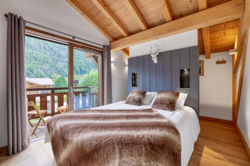 ein Schlafzimmer mit einem Bett und einem großen Fenster in der Unterkunft Chalet Paradis Blanc Morzine in Morzine