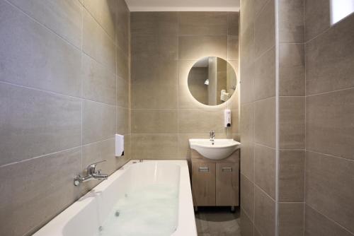 bagno con vasca, lavandino e specchio di Afroditi Hotel a Plakiás