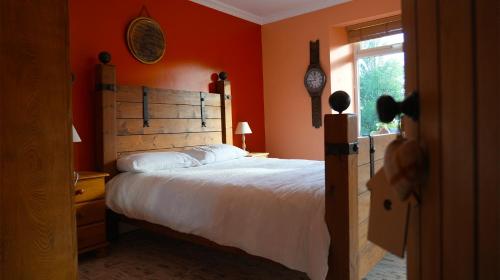a bedroom with a bed with orange walls and a window at Habititabities in Tenby