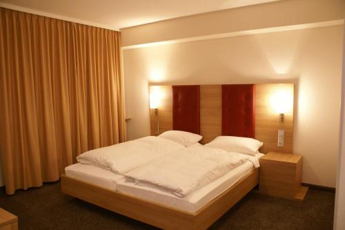 een slaapkamer met een groot bed met witte lakens bij Haus Hennche in Siegen