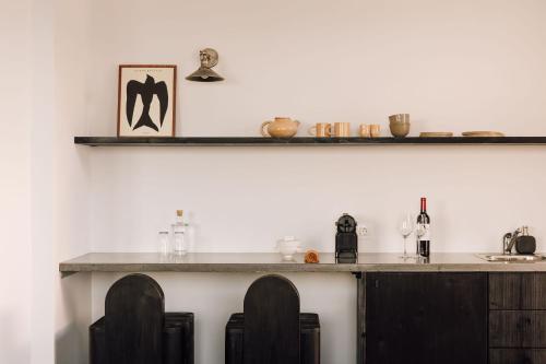 a bar with two chairs and a counter with wine glasses at White Exclusive Suites & Villas in Lagoa