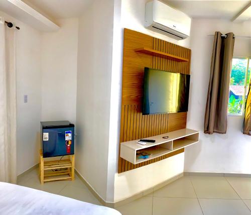 um quarto com uma televisão numa parede com uma cama em MATURI CENTRO em Pipa