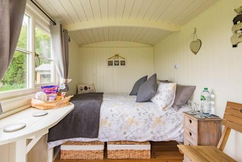 a bedroom with a bed and a desk and a window at Moss Shepherd's Hut by Bloom Stays in Egerton