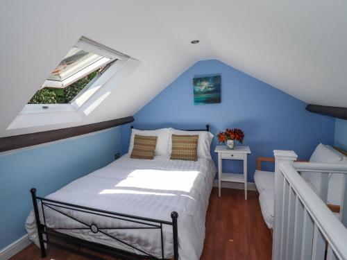een bed in een blauwe kamer met een raam bij Roecliffe in Boroughbridge