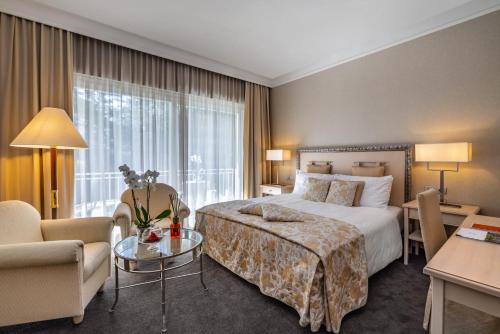 a hotel room with a bed and a table and chairs at Villa Eden a member of Leading Hotels of the World in Merano