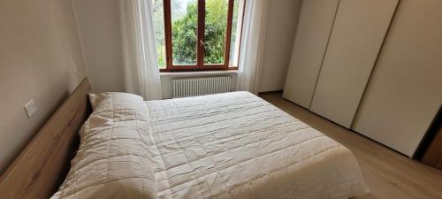 Bett in einem Schlafzimmer mit Fenster in der Unterkunft Ca' de l'Achille in Torri del Benaco